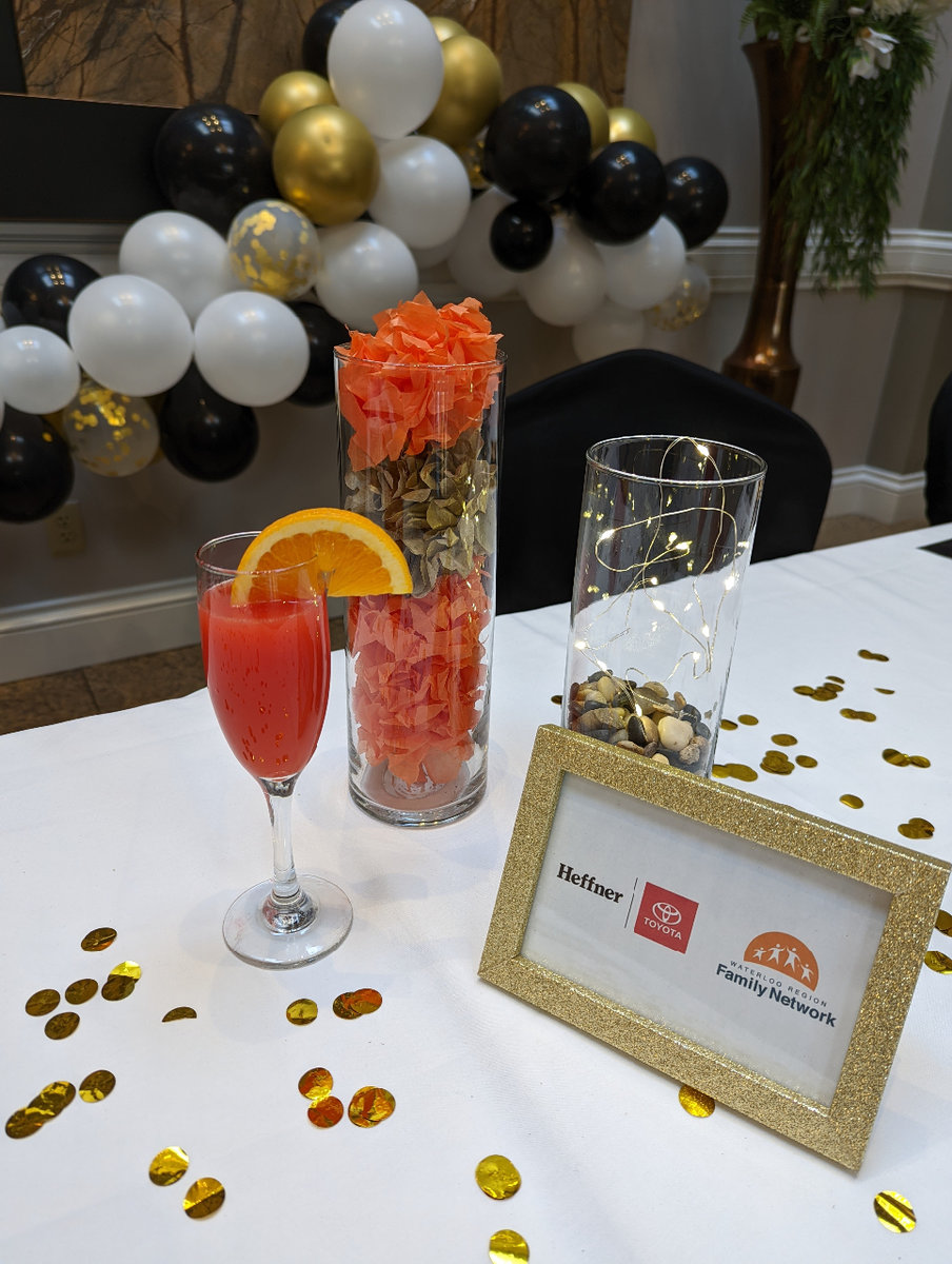 A decorated table with an orange drink and a picture frame beside it